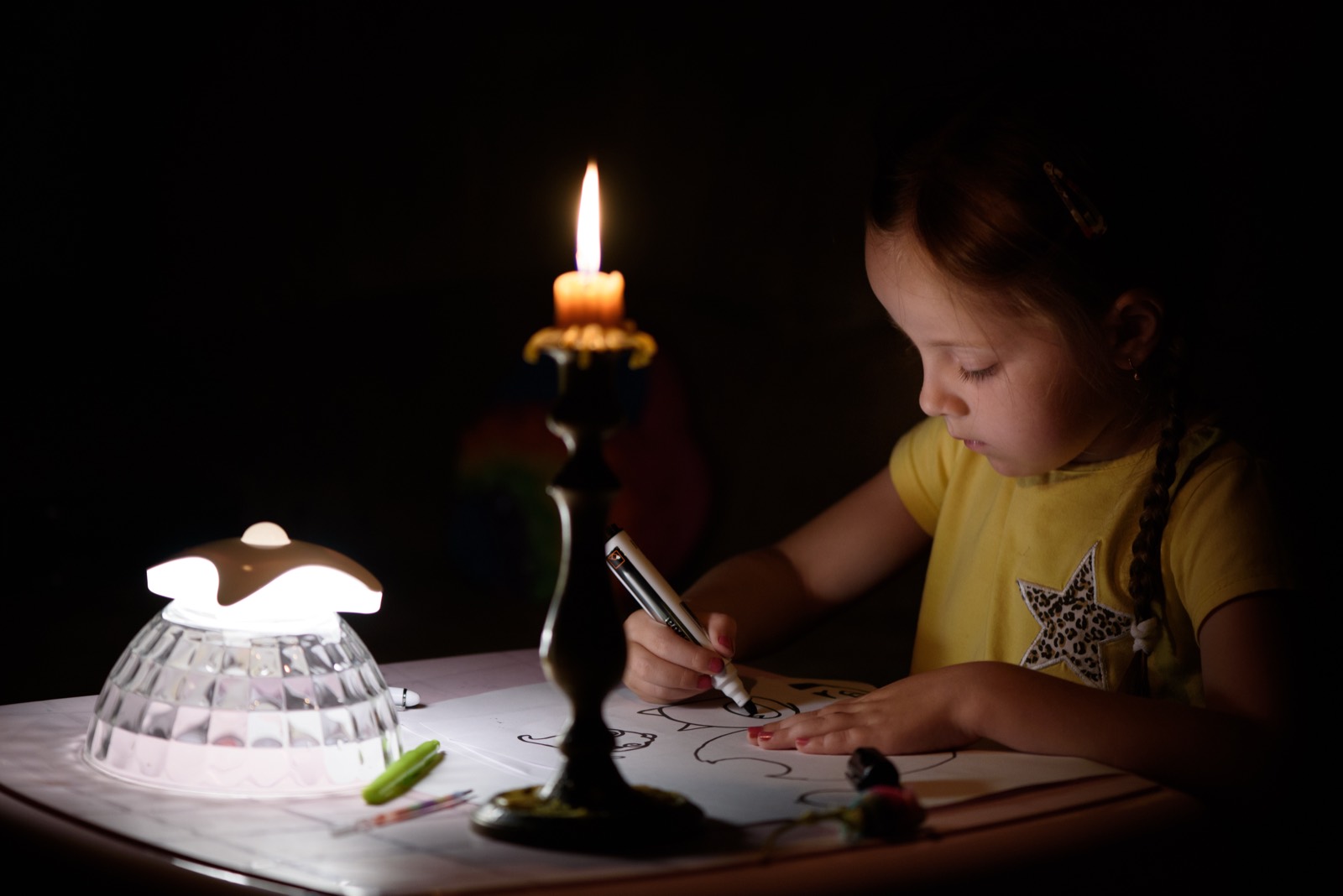 A child doing homework by candlelight during a power outage